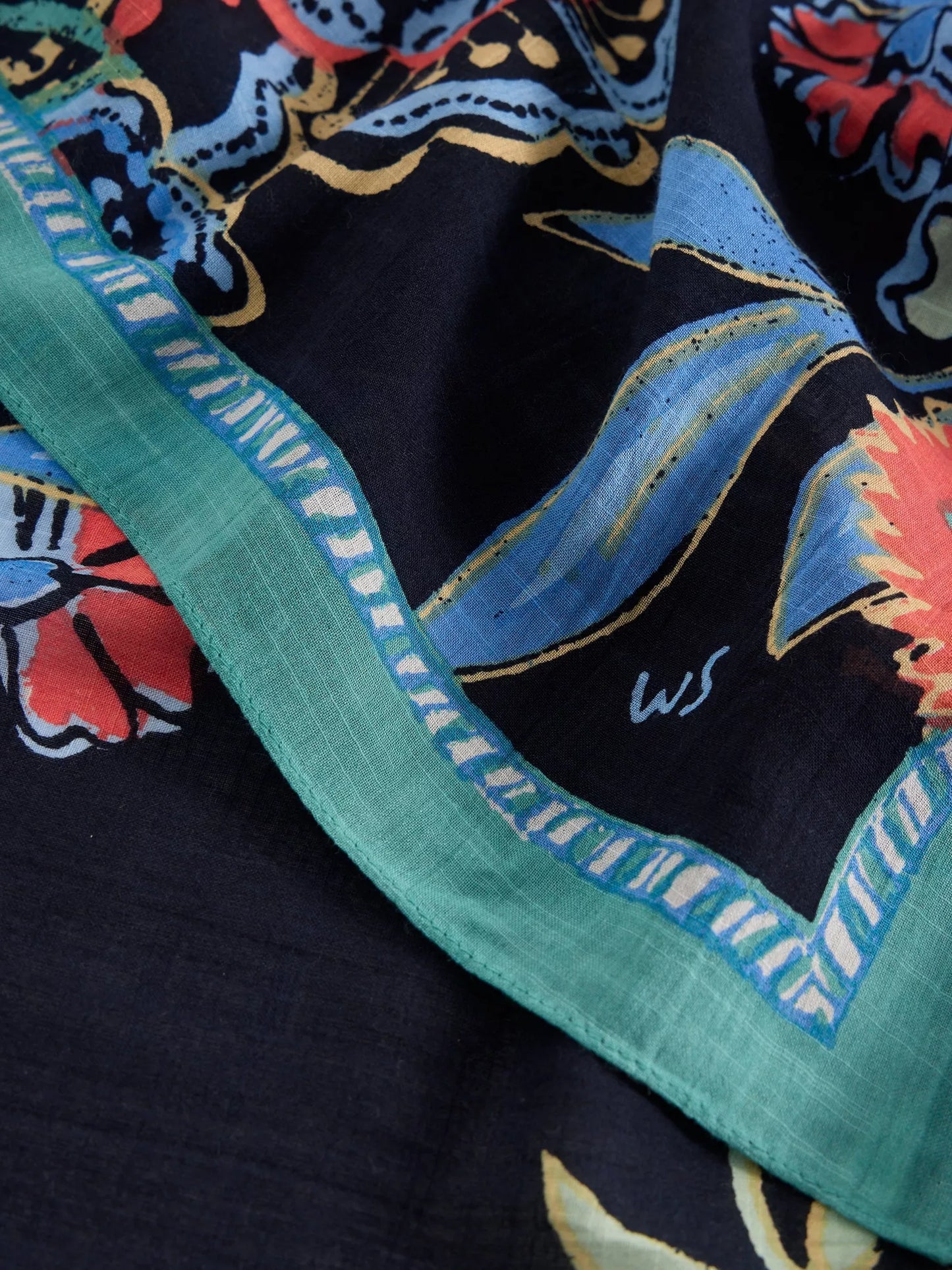 Close-up of a colorful fabric with floral patterns and a green border.