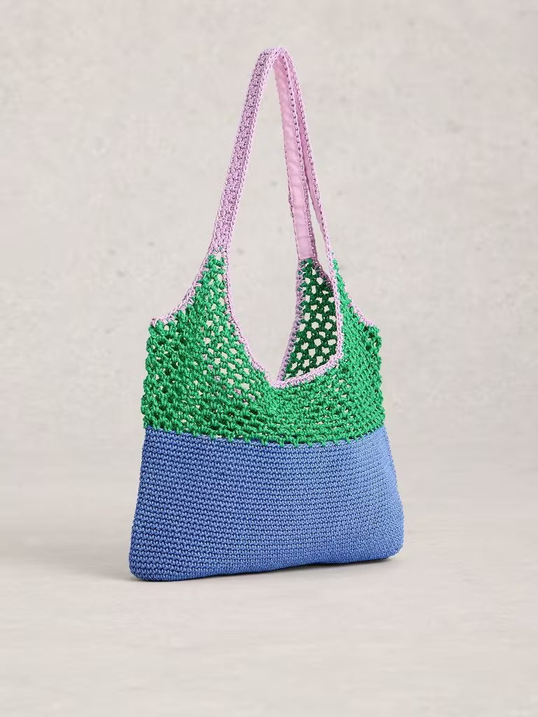 Crocheted bag with green top half and blue bottom half on a beige background