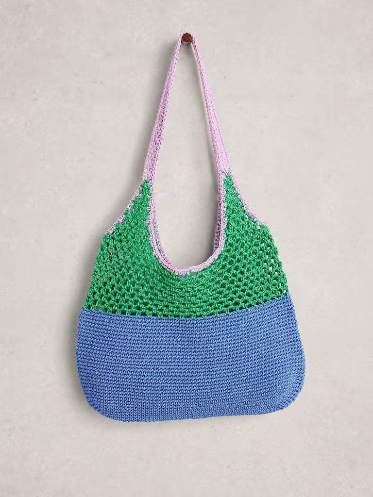 Crocheted bag with green top half and blue bottom half on a beige background