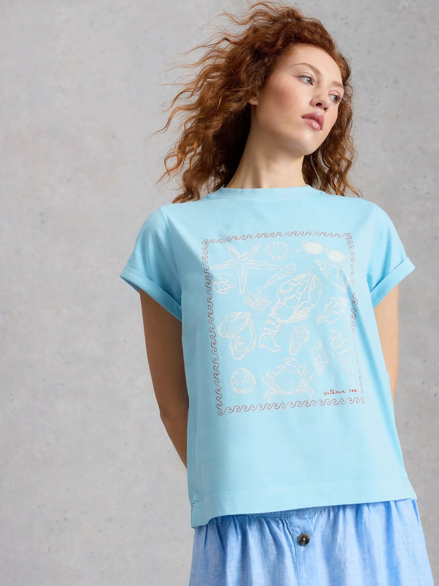 Woman wearing a light blue t-shirt with a subtle pattern on a plain background