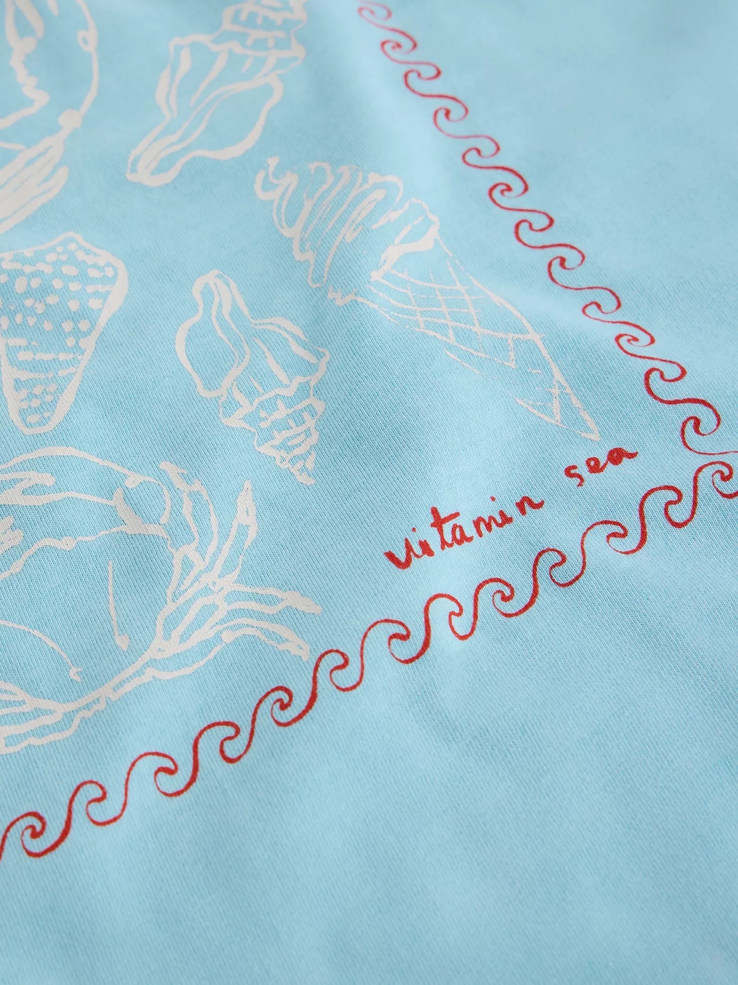 Light blue fabric with white shell patterns and red text 'vitamin sea' on a light blue background