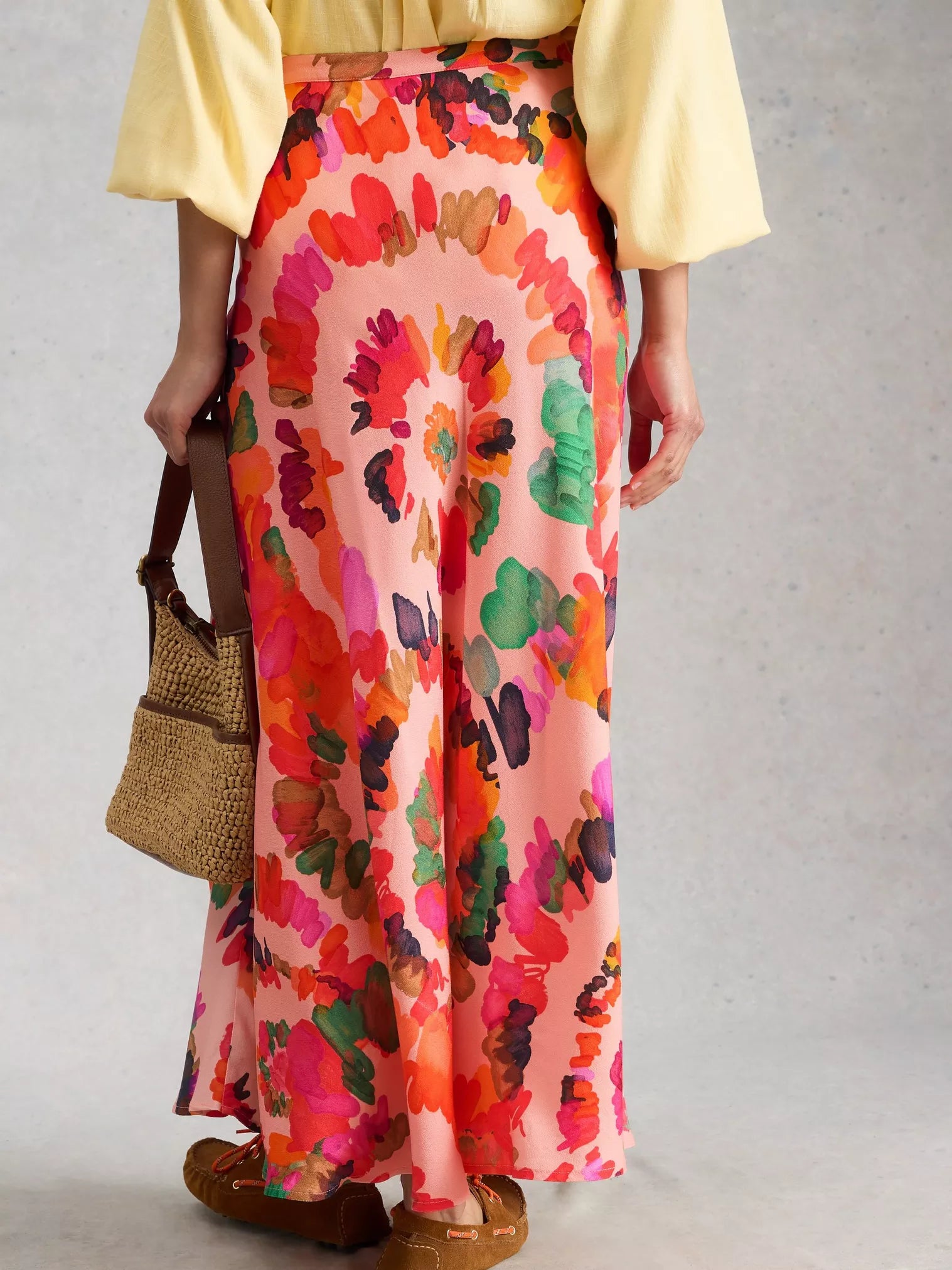 Person wearing a colorful floral skirt with a plain background