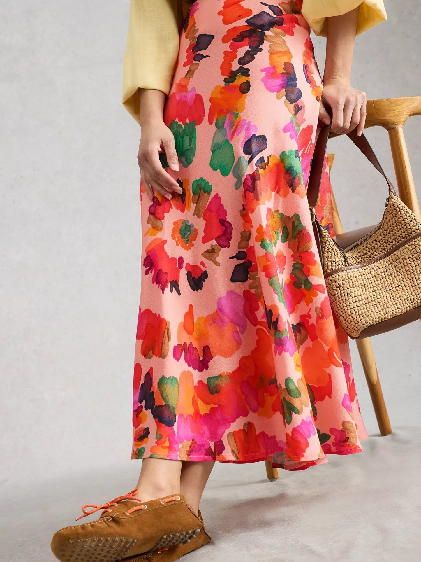 Person wearing a colorful floral dress with a neutral background