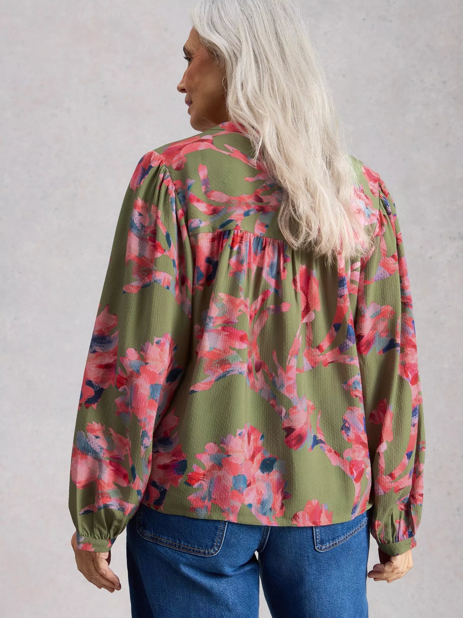 Person wearing a floral blouse with long sleeves on a plain background