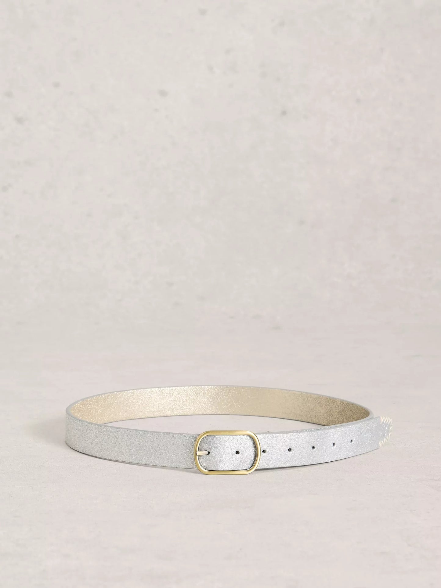 Silver leather belt with a gold buckle on a light grey background