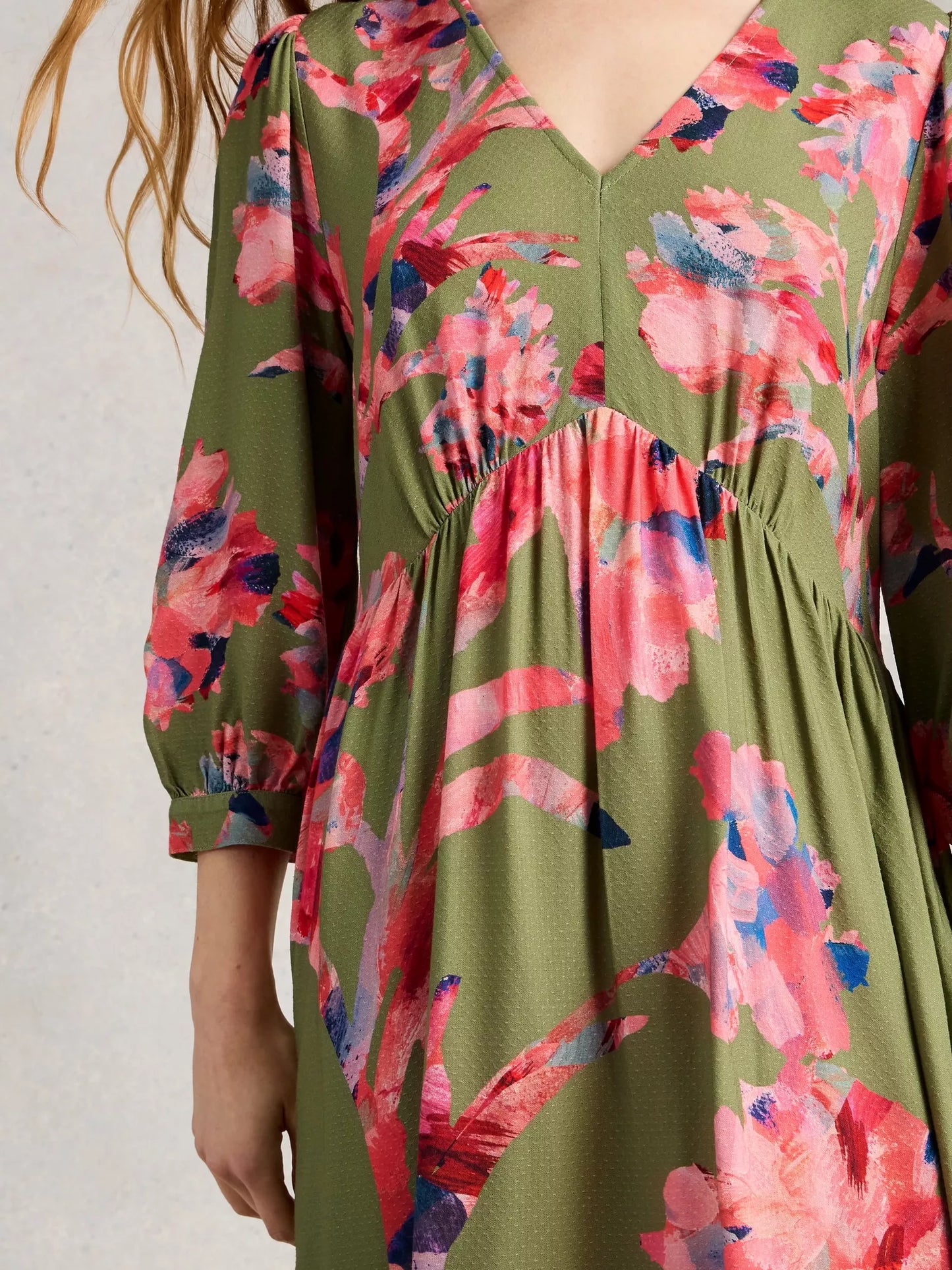 Green dress with pink floral pattern on a plain background