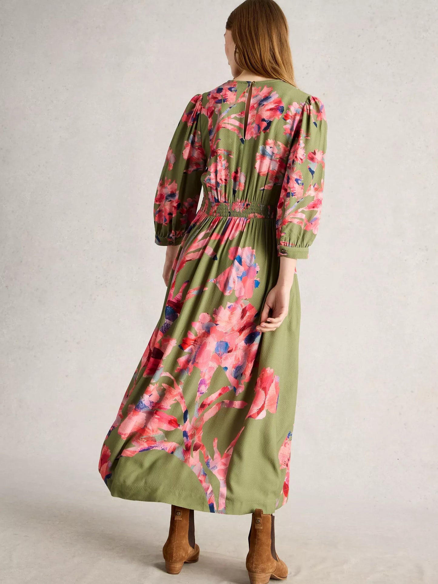 Woman wearing a long floral dress with a plain background