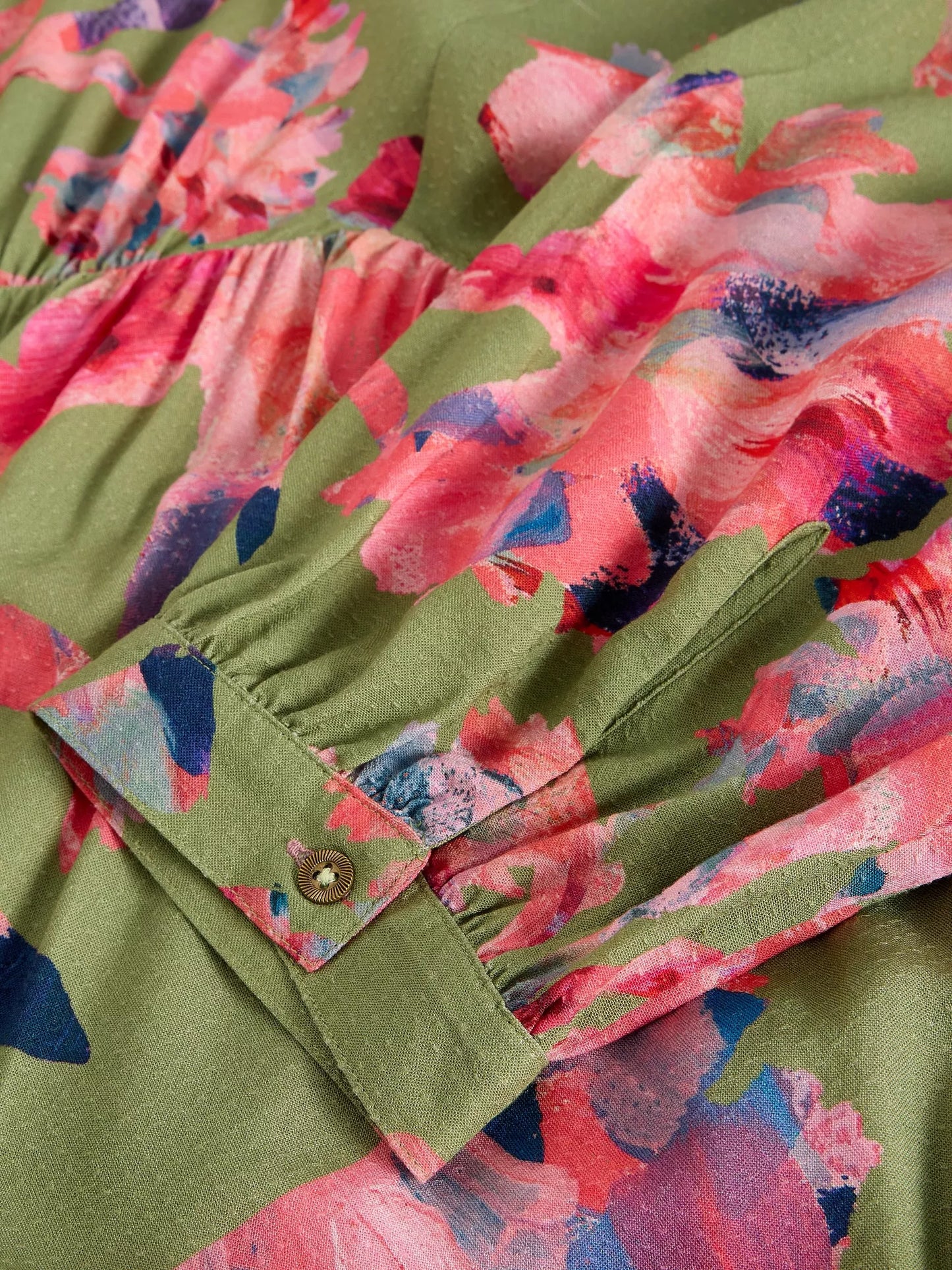 Close-up of a green fabric with pink and blue floral pattern