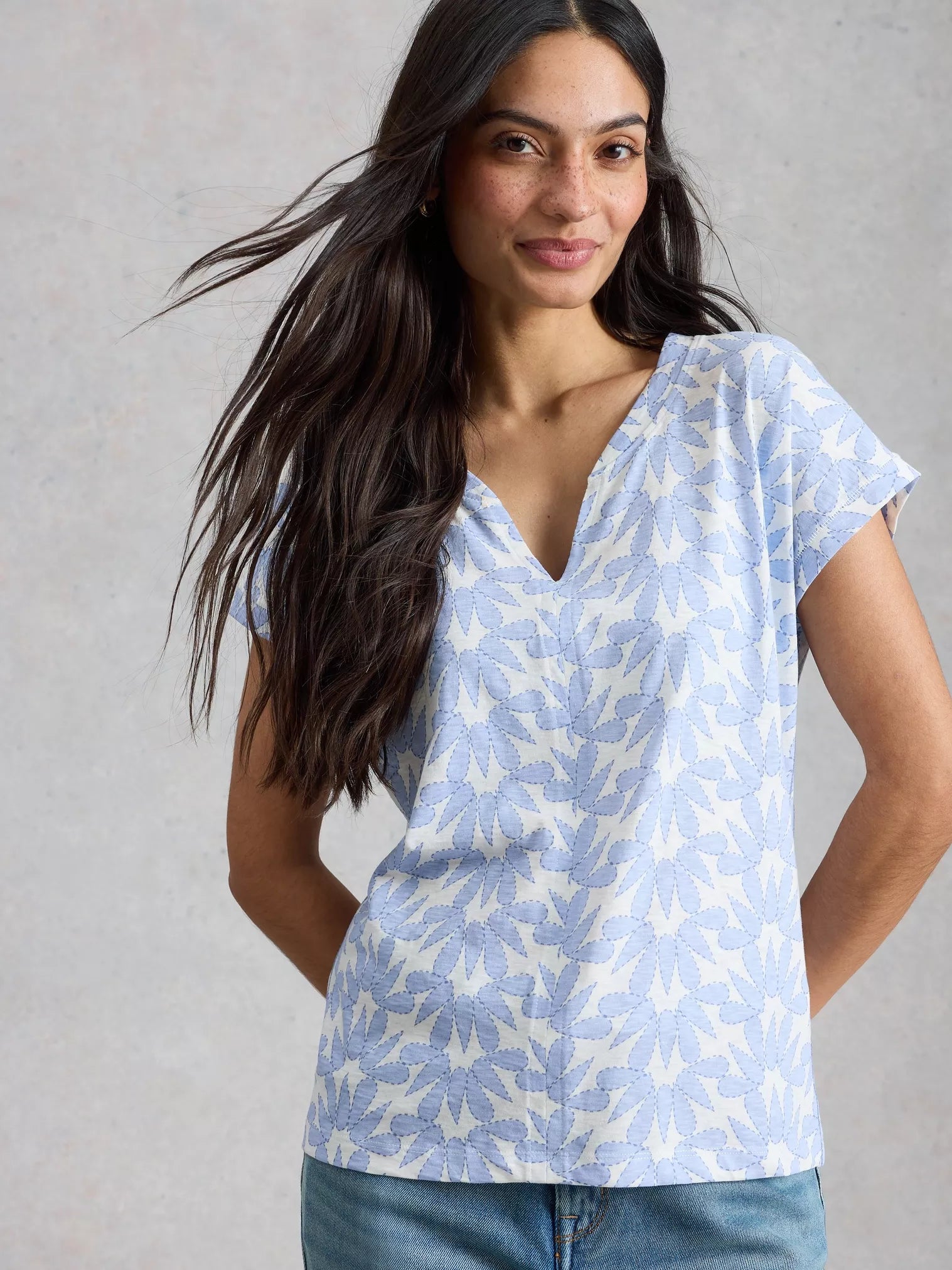 Woman wearing a light blue patterned shirt against a gray background