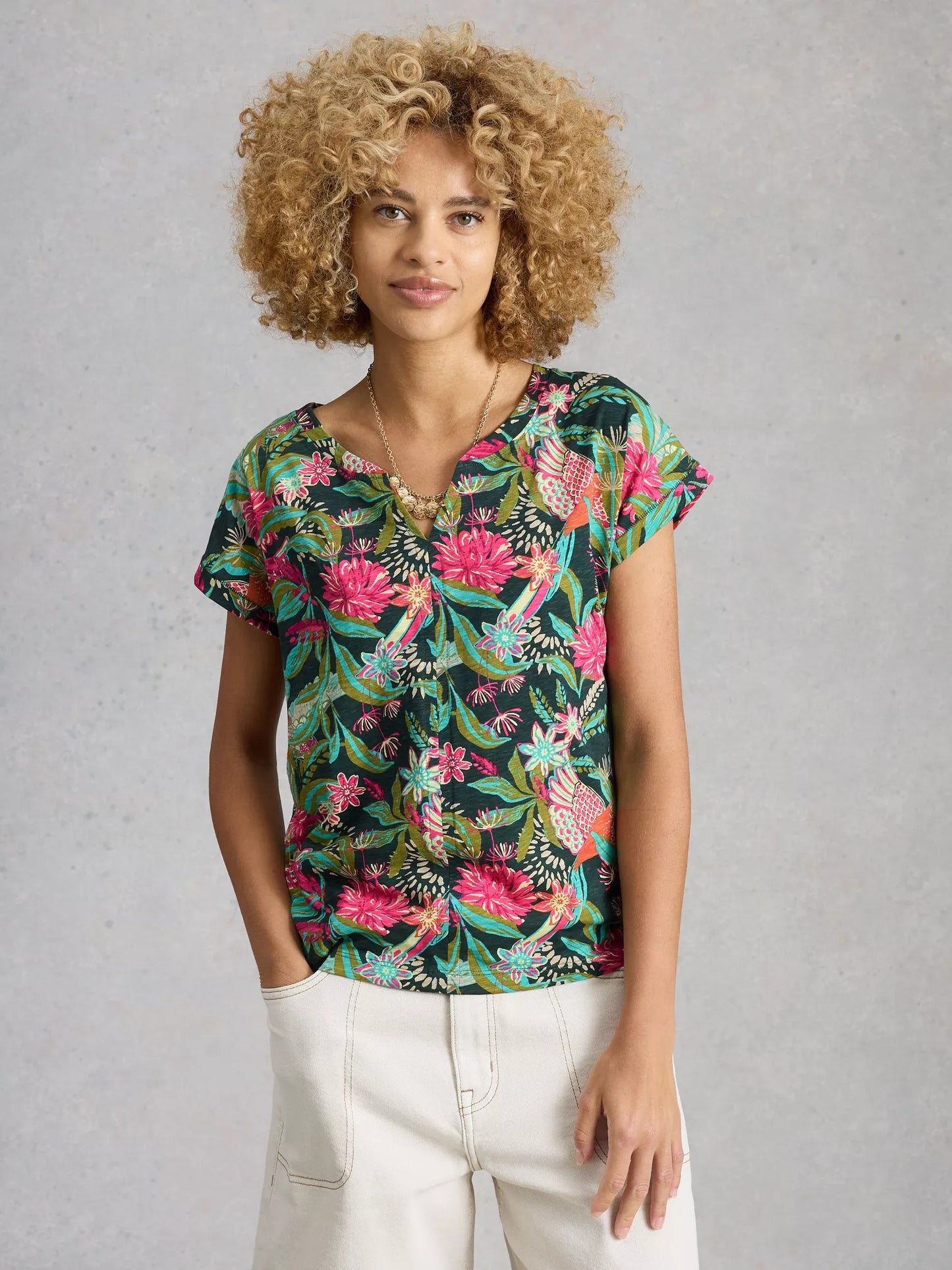 Woman wearing a colorful floral blouse against a gray background