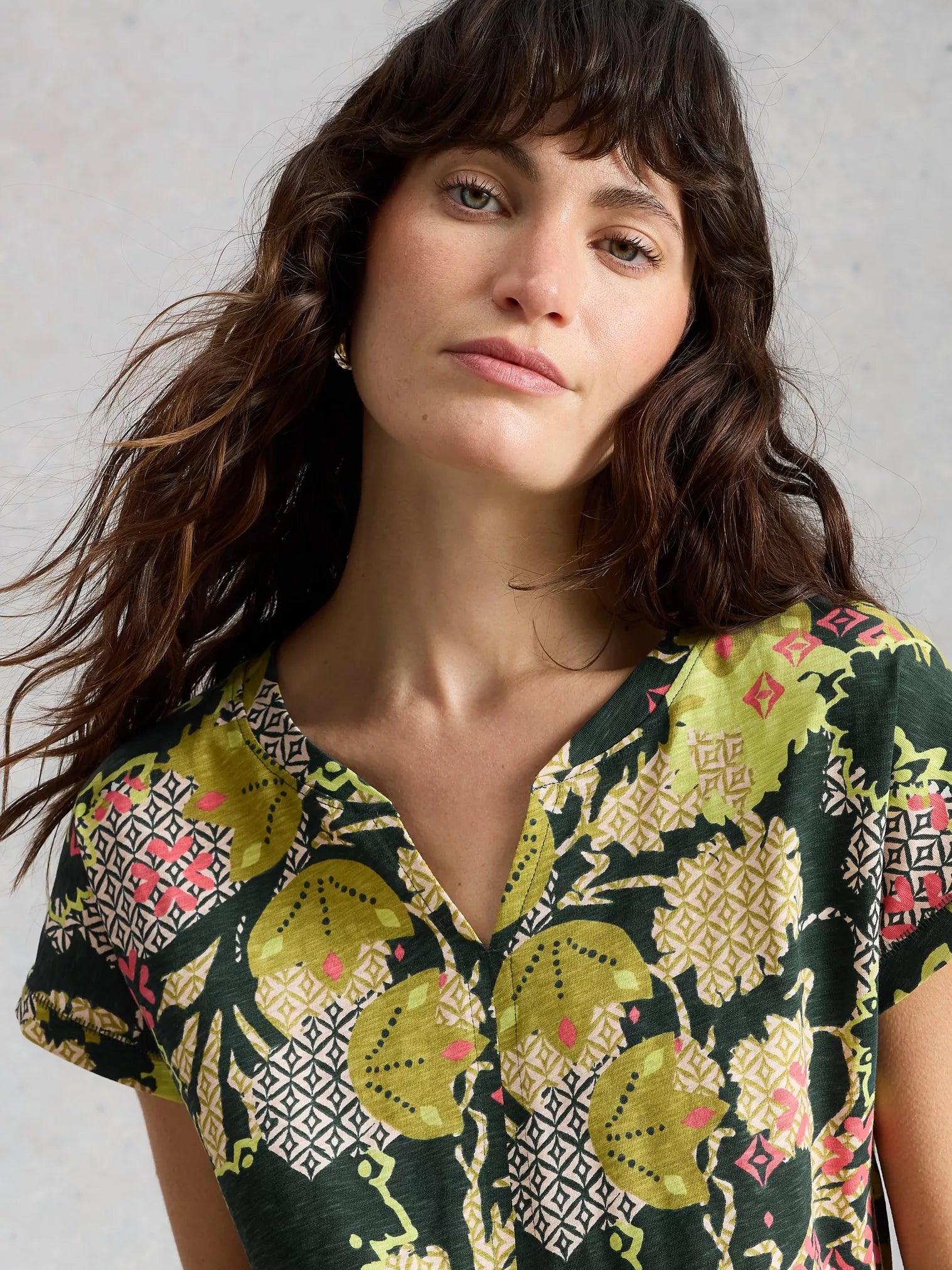 Woman wearing a patterned shirt with a neutral background