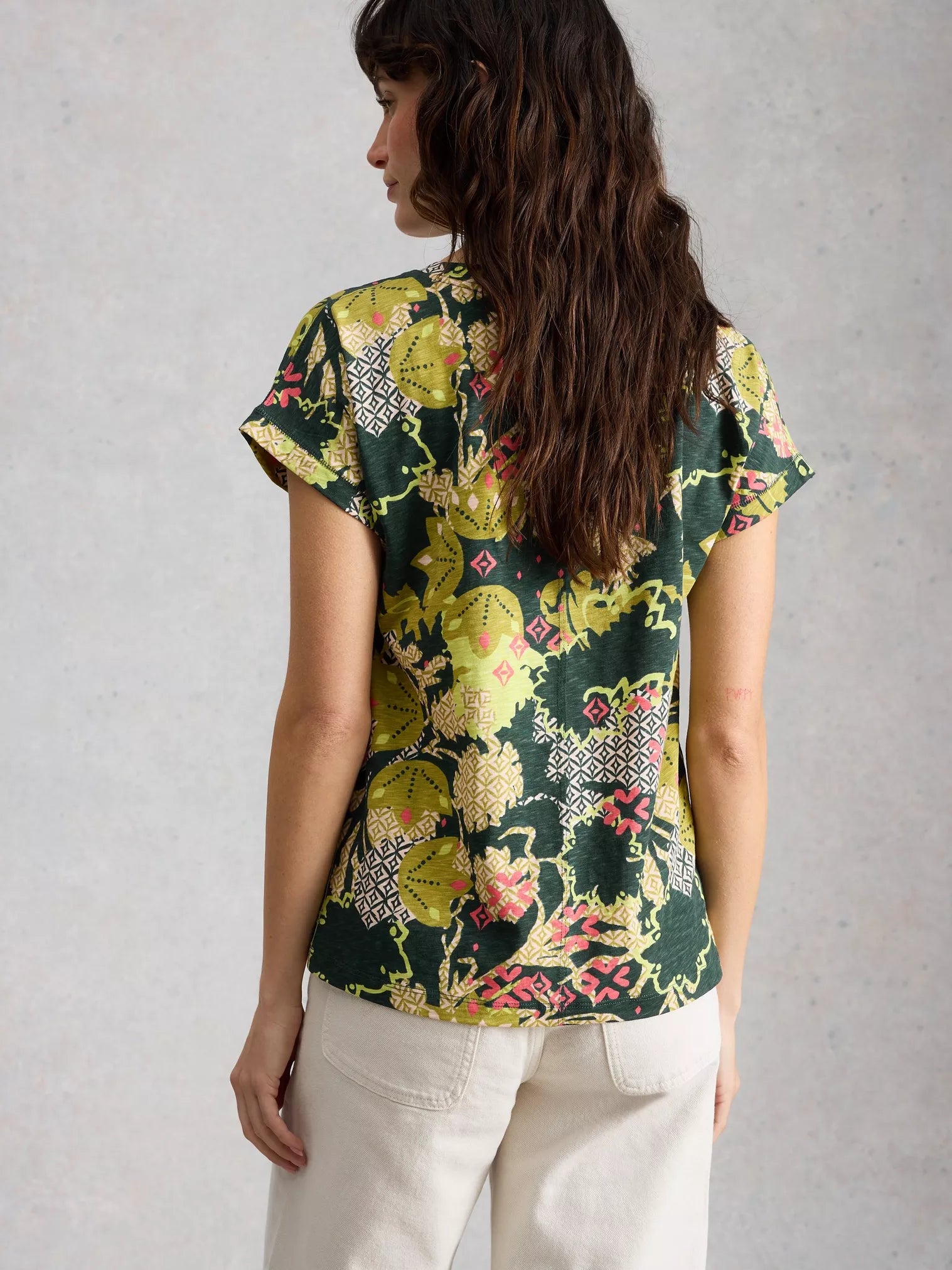 Woman wearing a floral patterned top against a plain background