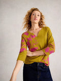 Woman wearing a green and pink floral blouse against a plain background
