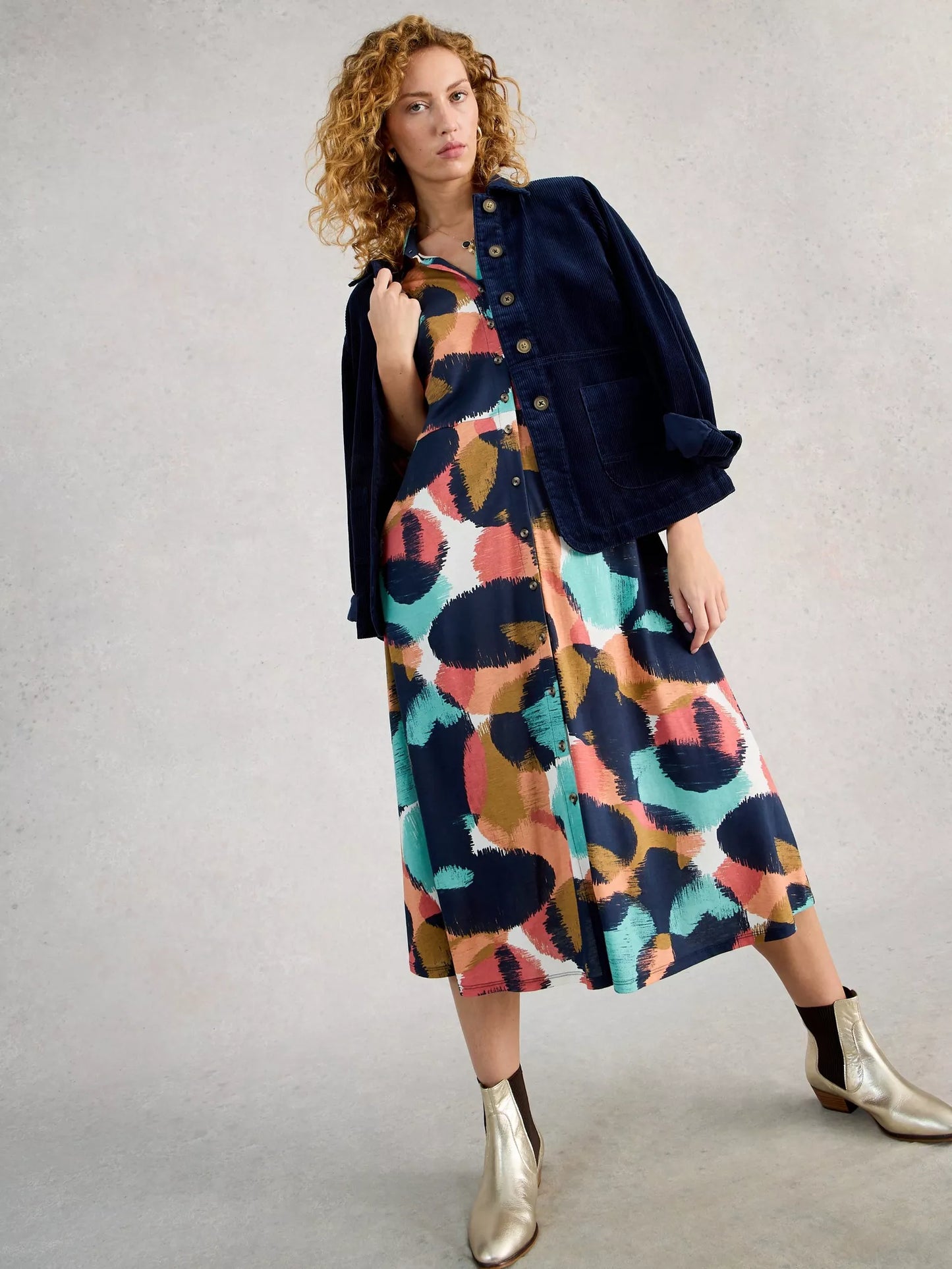 model in multi shirt dress with gold boots and navy jacket