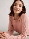 Woman wearing a pink long-sleeve top against a light background