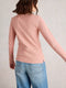 Person wearing a pink long-sleeve top and blue jeans on a plain background