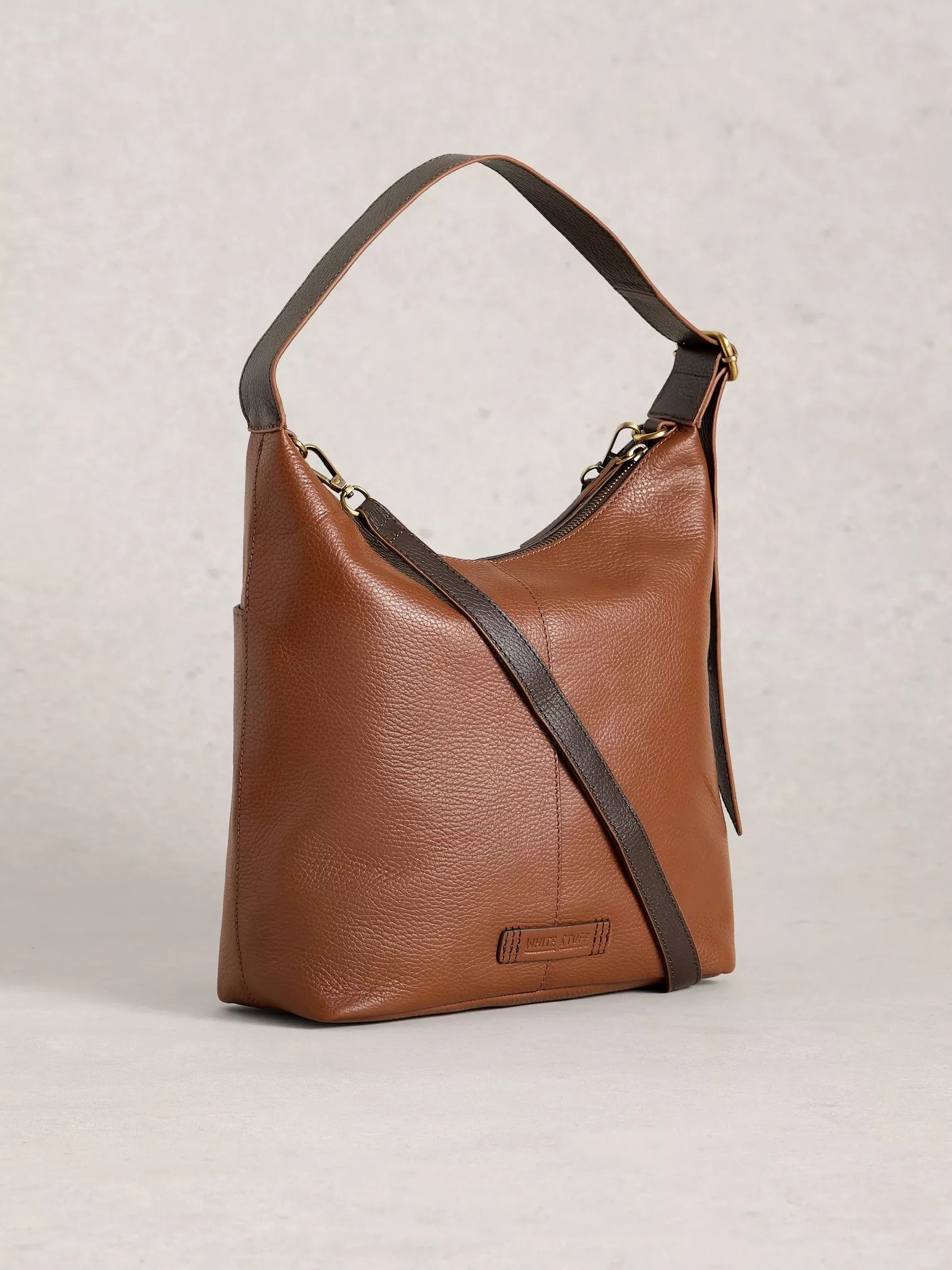 Brown leather handbag with a shoulder strap on a light gray background