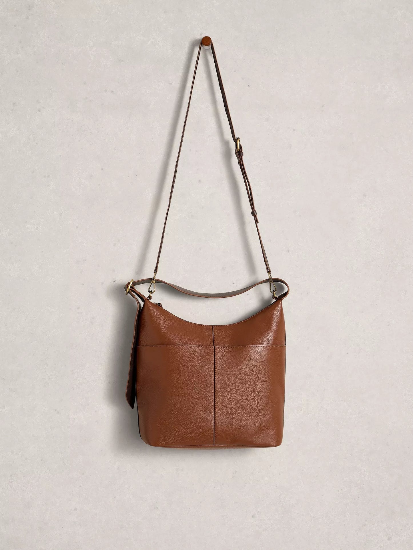 Brown leather handbag with a strap on a light gray background