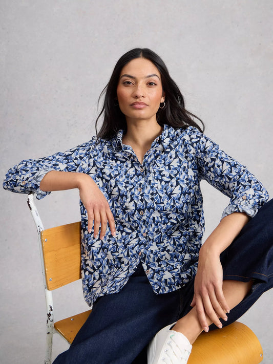 Model on a chair wearing navy shirt with blue and white heart print