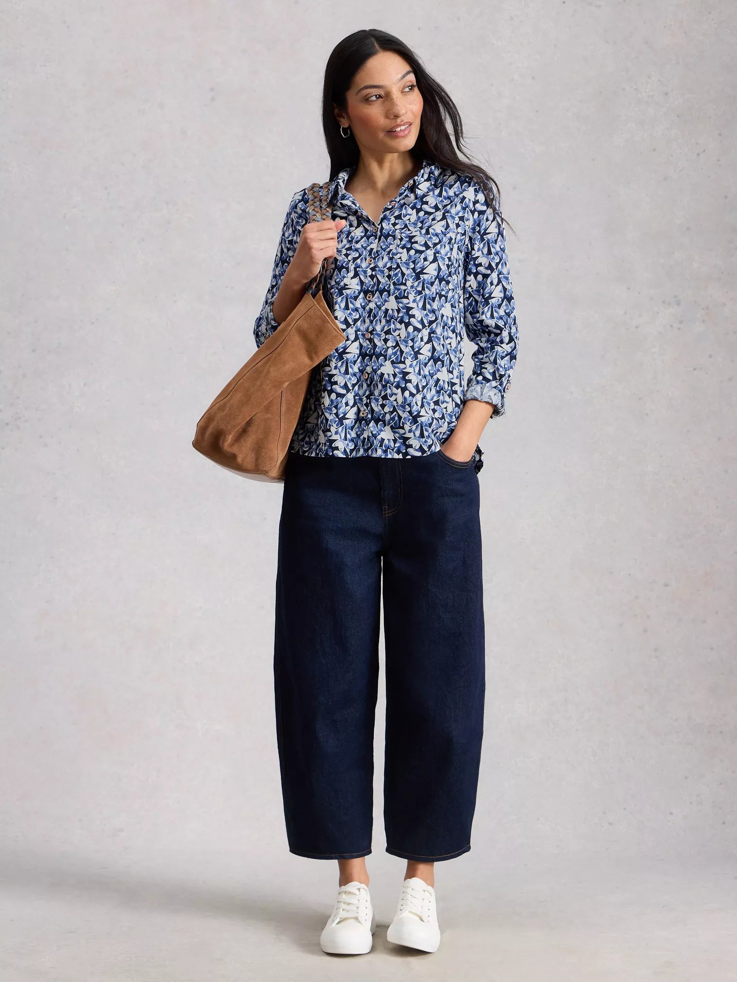 Model in navy shirt with jeans and white pumps