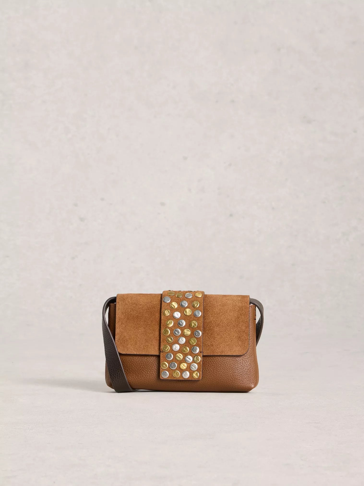 Brown handbag with decorative studs on a light gray background