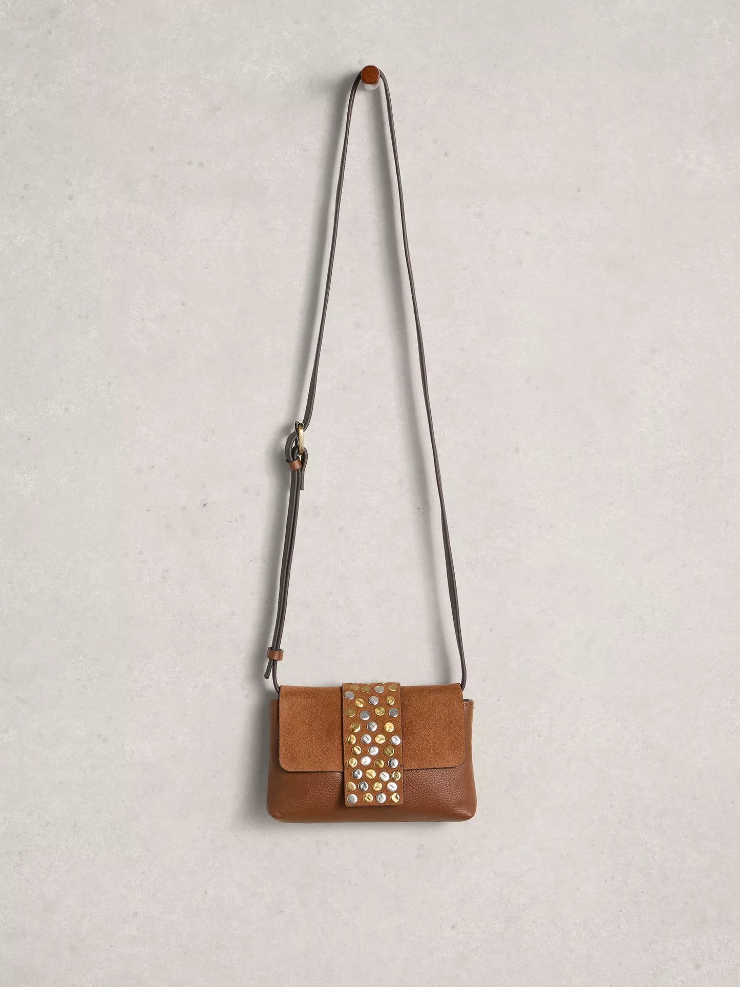 Brown leather handbag with studded detail on a light gray background
