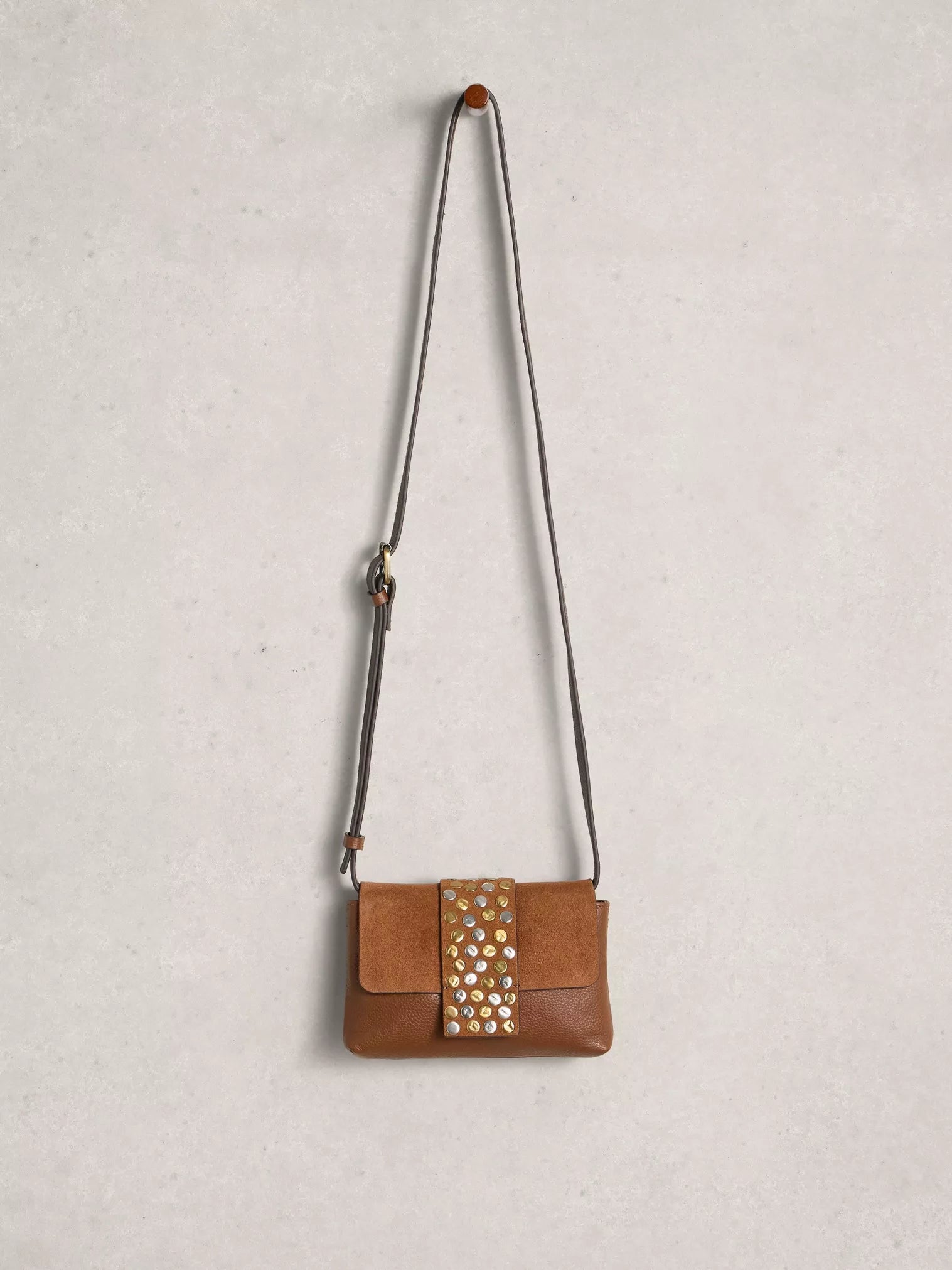 Brown leather handbag with studded detail on a light gray background