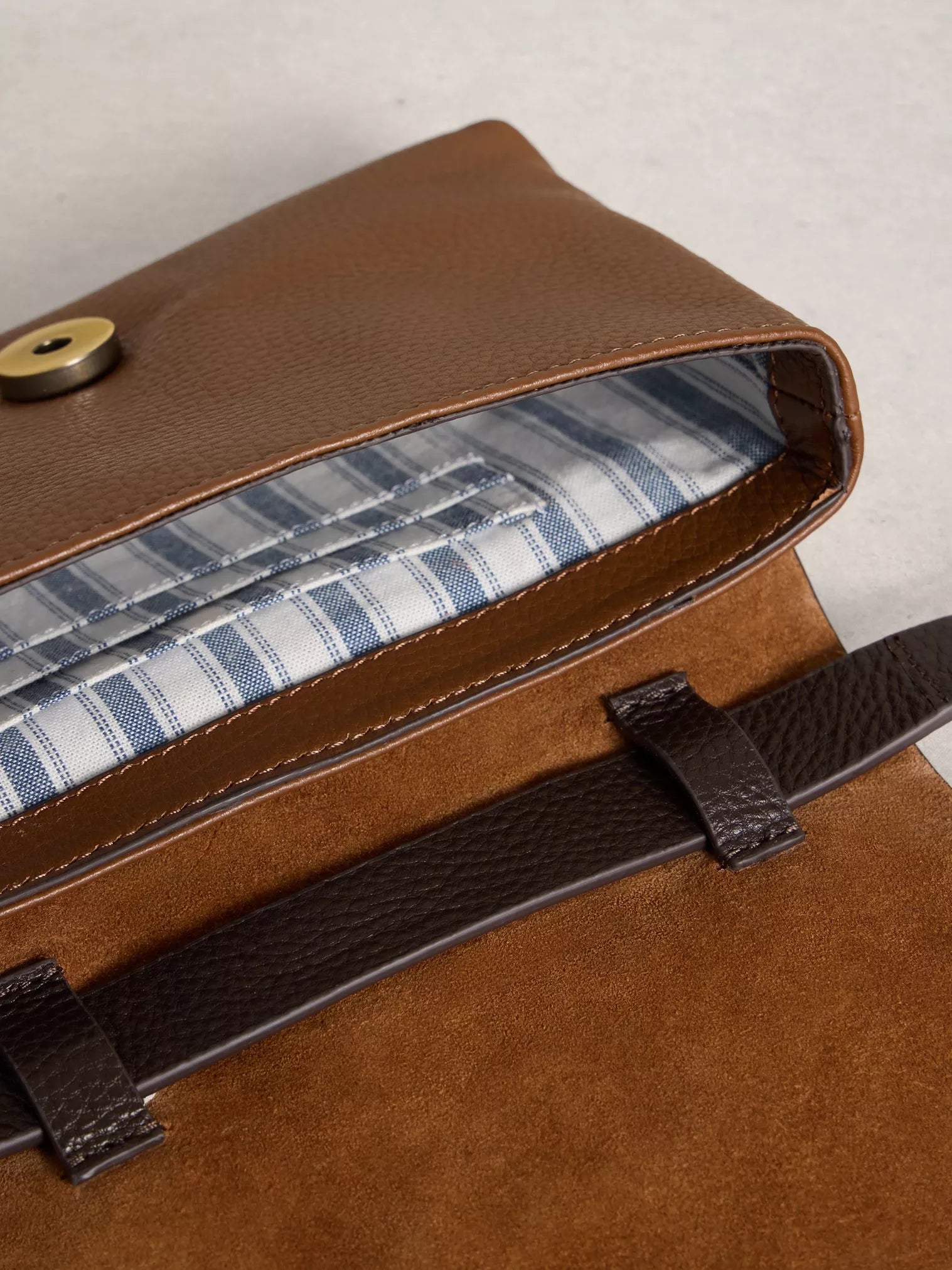 Brown leather bag with striped lining on a light background