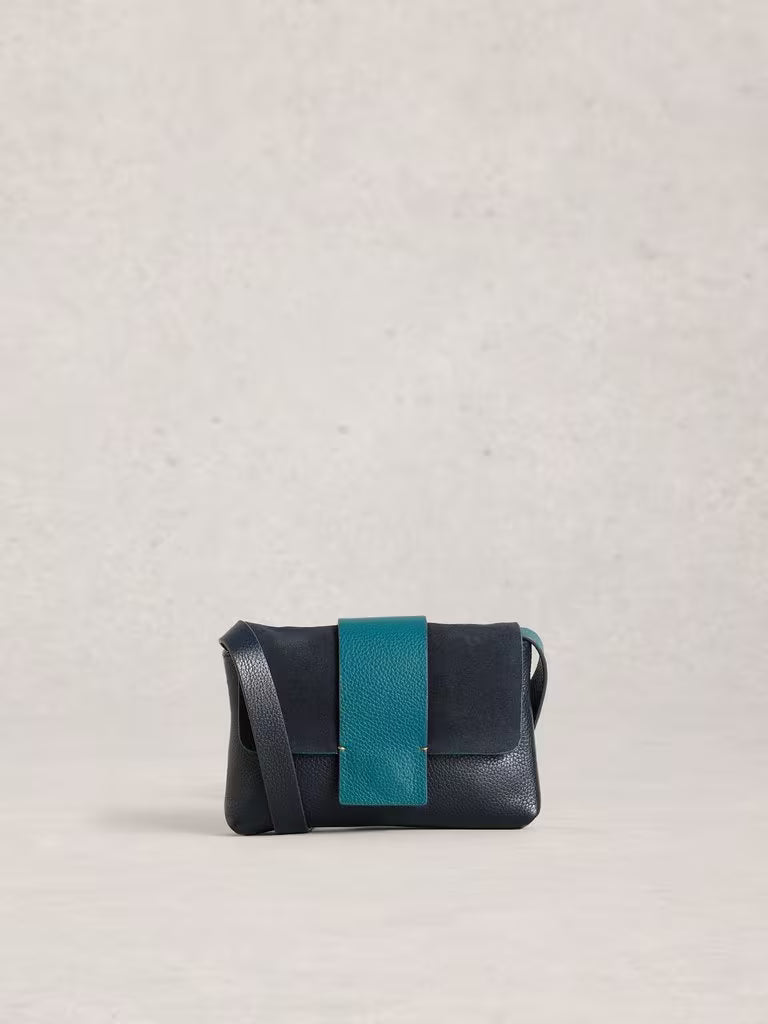 Navy leather handbag with a turquoise strap on a light grey background