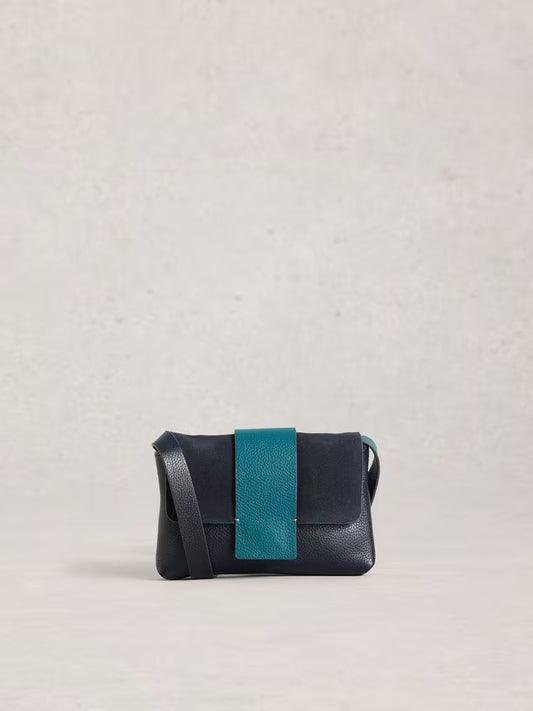 Navy leather handbag with a turquoise strap on a light grey background