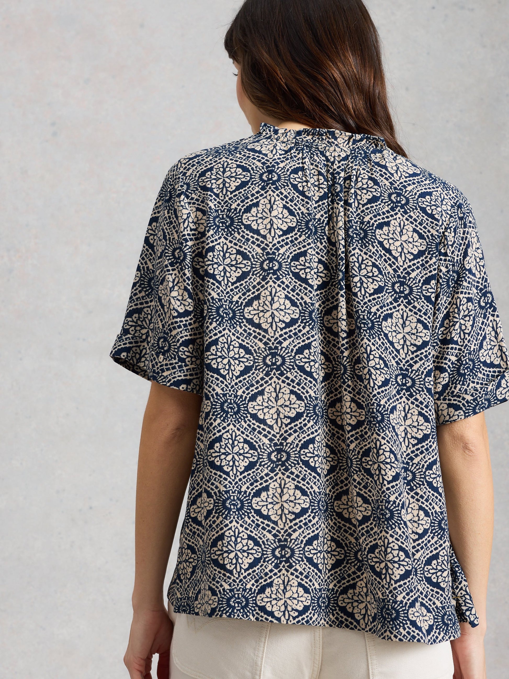 Person wearing a patterned shirt with a neutral background