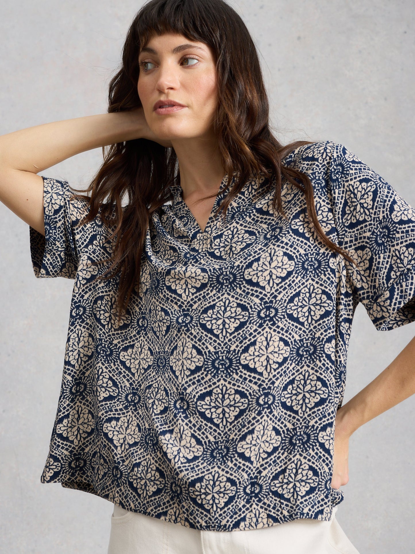 Woman wearing a patterned blouse against a plain background