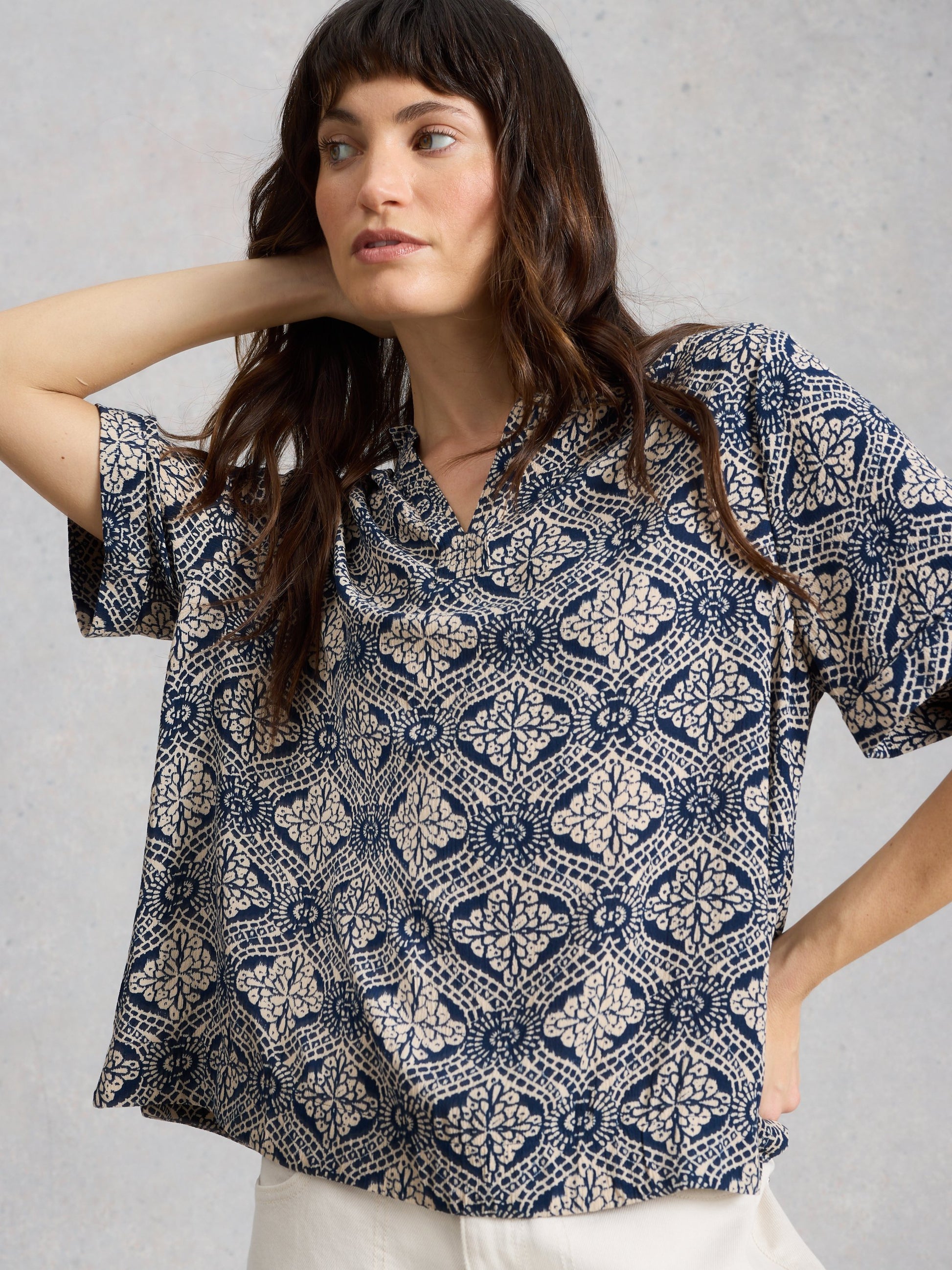 Woman wearing a patterned blouse against a plain background