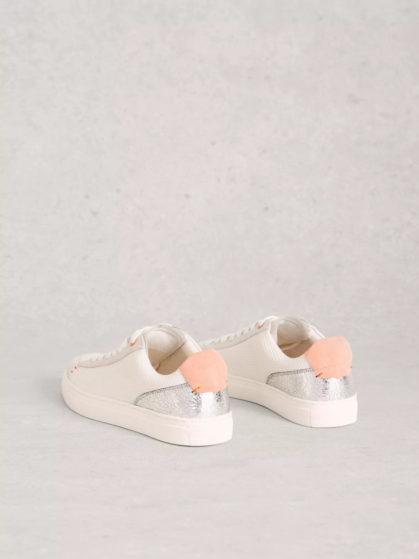 White sneakers with pink accents on a light gray background
