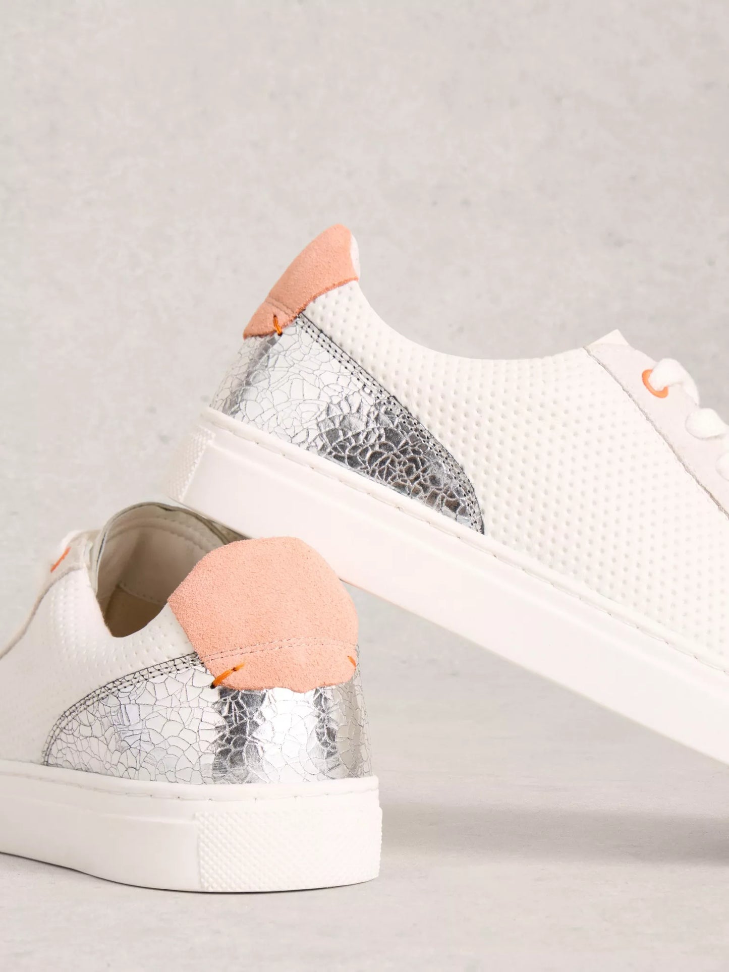 Pair of silver and white sneakers on a light gray background