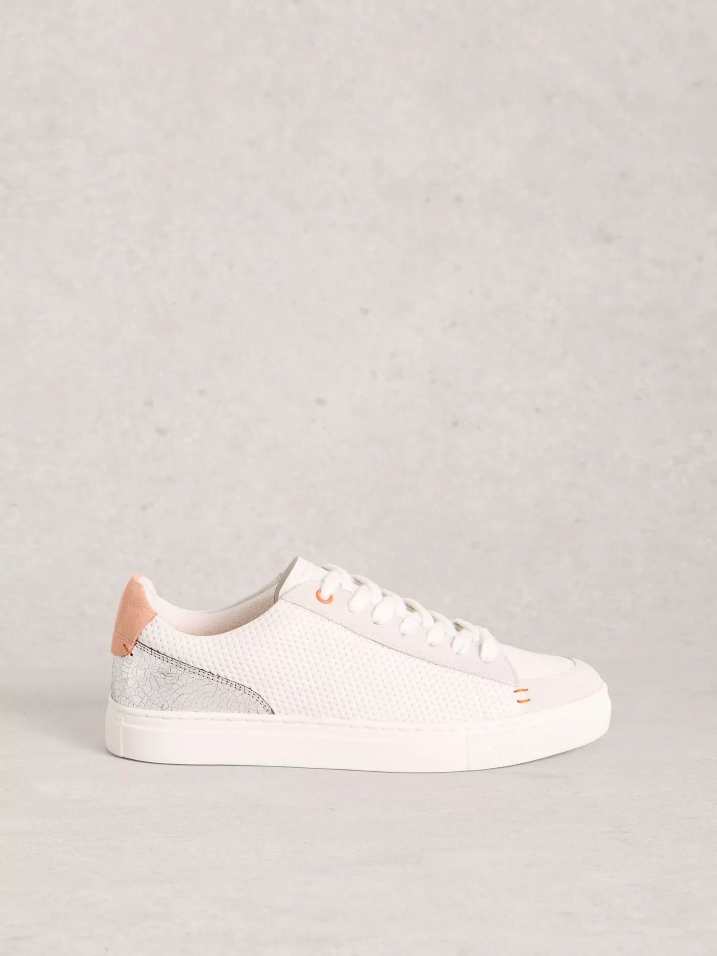 White sneaker with pink accents on a light gray background