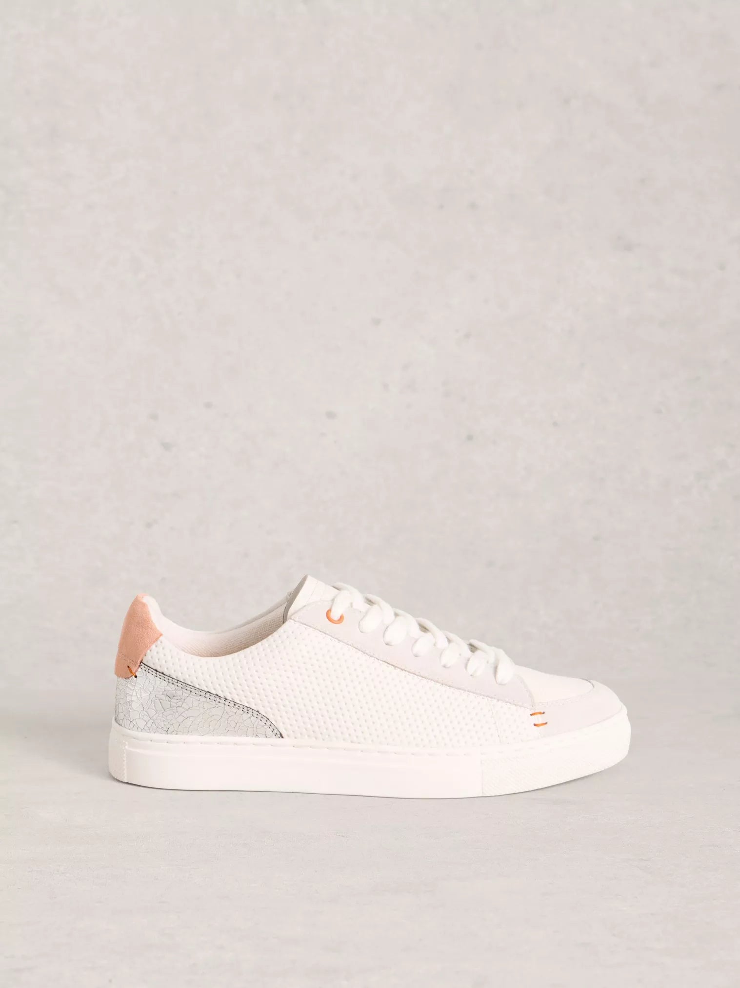 White sneaker with pink accents on a light gray background