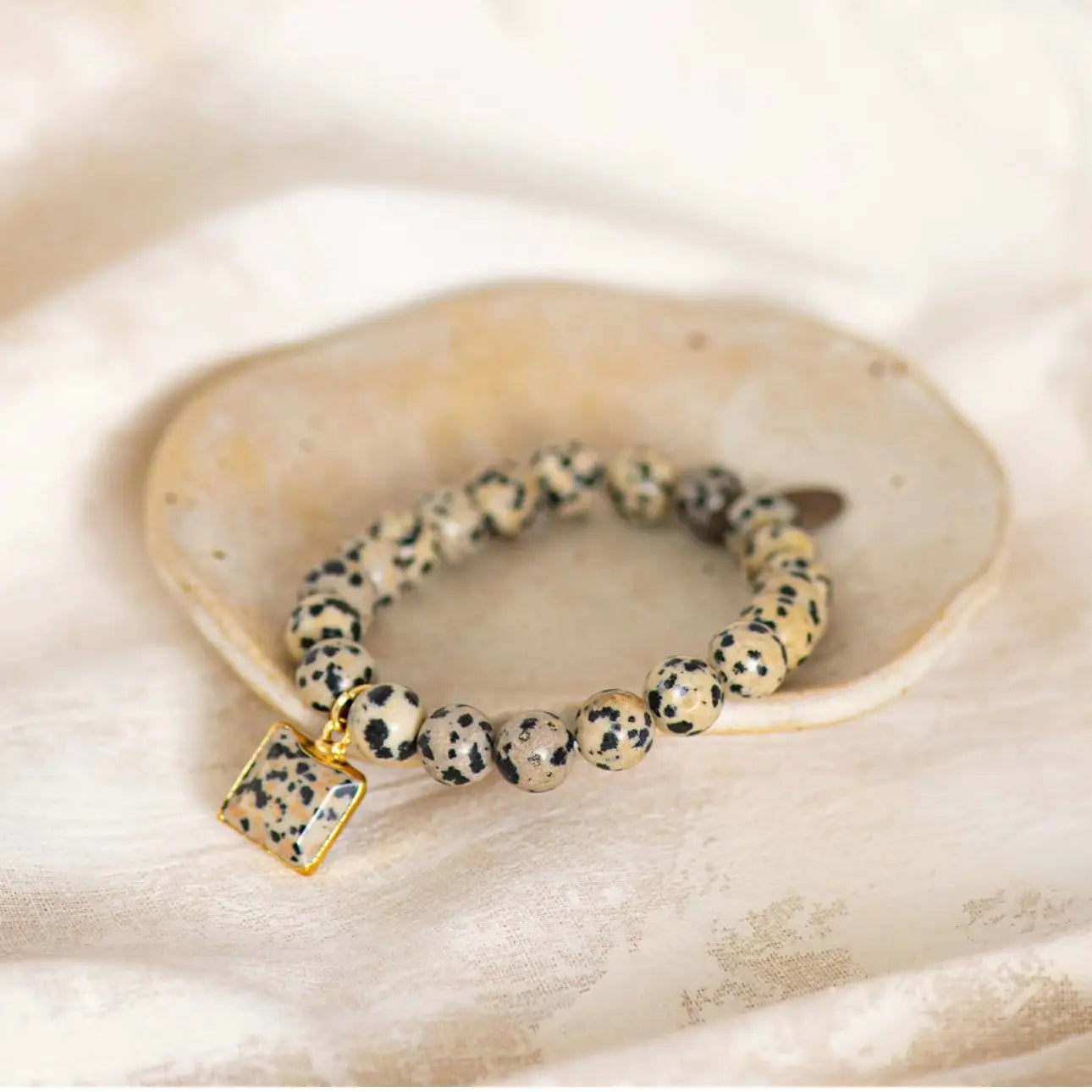 Beaded bracelet with a gold clasp on a textured beige surface