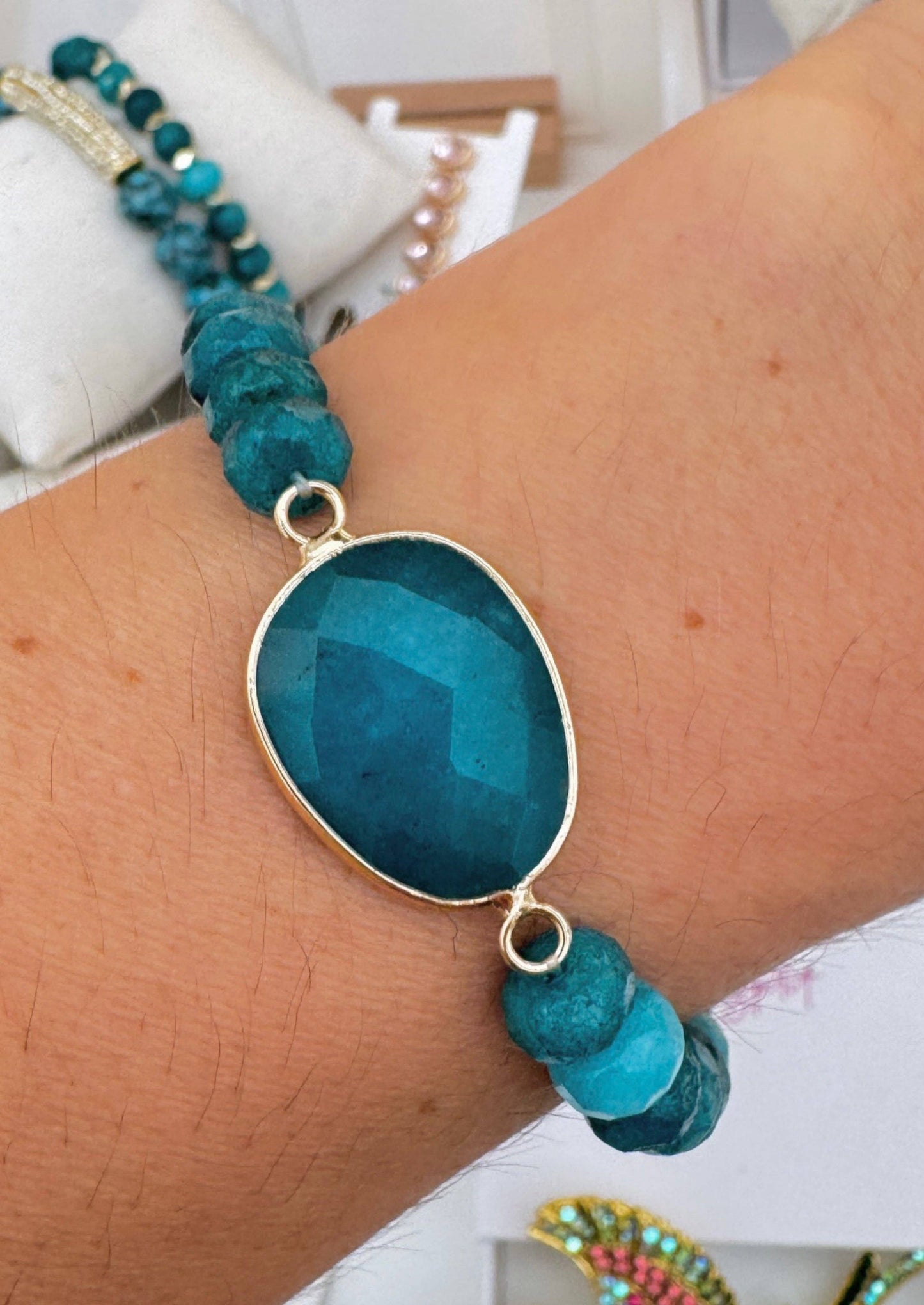 Turquoise beaded bracelet with a large blue stone on a wrist.