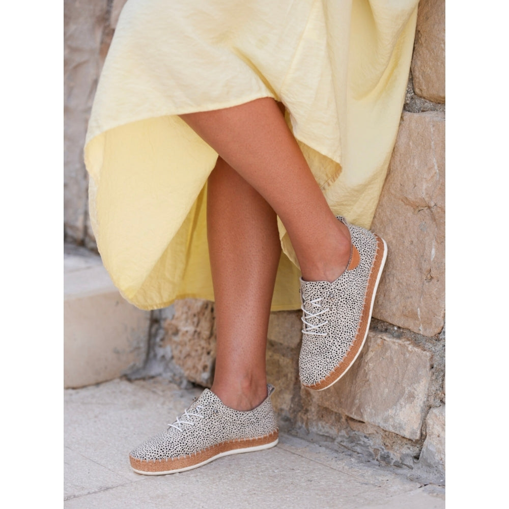 Person wearing sparkly sneakers with a yellow dress in a stone setting
