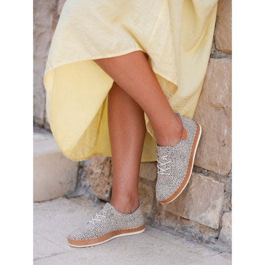 Person wearing sparkly sneakers with a yellow dress in a stone setting