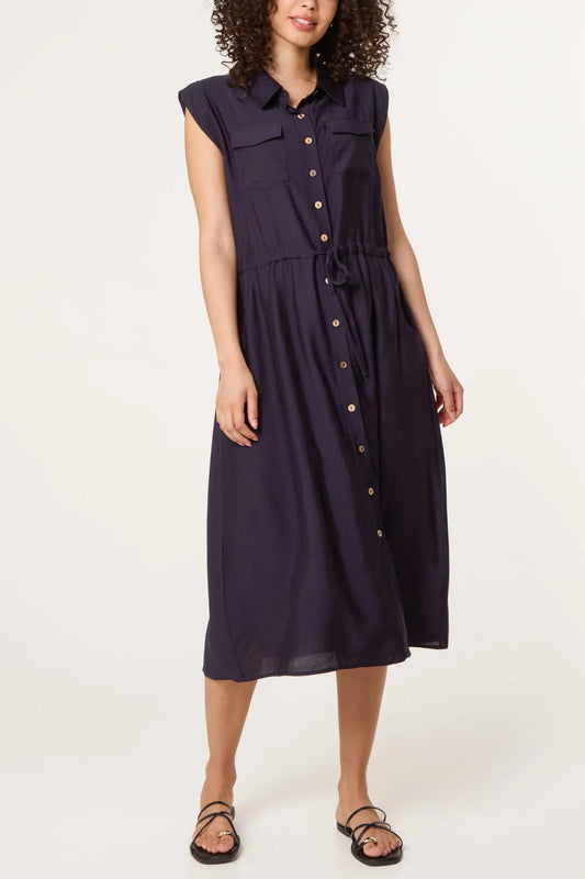 Woman wearing a navy sleeveless dress with buttons on a white background